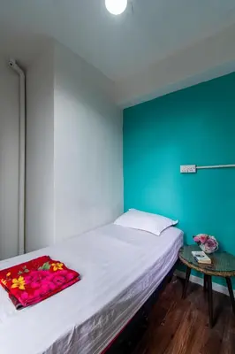 a bedroom with a white bed with a blue wall at Travel Hub Guesthouse in Kuala Lumpur