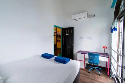 a bedroom with a bed and a desk and a chair at Travel Hub Guesthouse in Kuala Lumpur