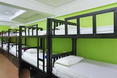 a row of bunk beds in a room with green walls at Travel Hub Guesthouse in Kuala Lumpur