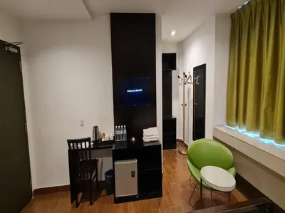 a living room with a green chair and a desk at Hotel O Crossroads Hotel in Kuala Lumpur