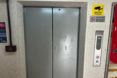 a metal door in a room with a sign on a wall at Sha La La Hostel in Kuala Lumpur