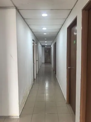 a hallway with a long corridor with white walls and white tile floors at Sha La La Hostel in Kuala Lumpur