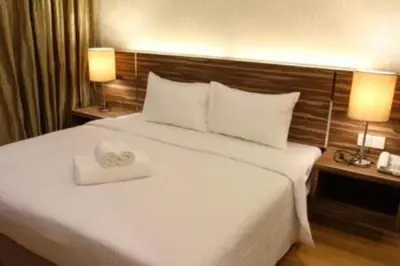 a bedroom with a large white bed with two towels on it at Regalia Upper View Hotel in Kuala Lumpur