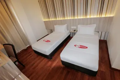 two beds in a small room with a chair at My Hotel @ KL Sentral in Kuala Lumpur