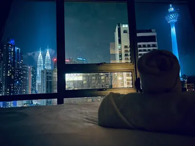 a bedroom with a view of a city at night at Modern 3BR with Iconic KLCC Towers Skyline Views and Parking in Kuala Lumpur