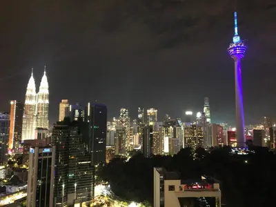 a view of a city at night with a purple tower at Modern 3BR with Iconic KLCC Towers Skyline Views and Parking in Kuala Lumpur