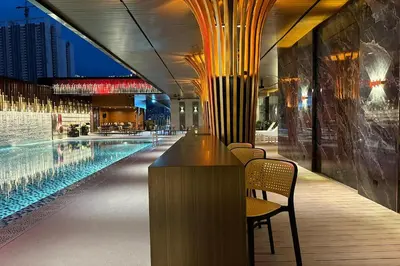 a swimming pool with chairs and a bar in a building at Vivatel Kuala Lumpur in Kuala Lumpur