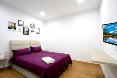 a bedroom with a purple bed and a tv at Zeta Desky in Kuala Lumpur