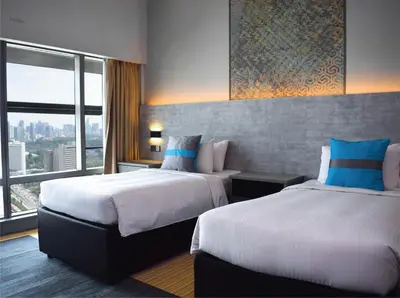 two beds in a hotel room with a large window at Premiera Hotel Kuala Lumpur in Kuala Lumpur