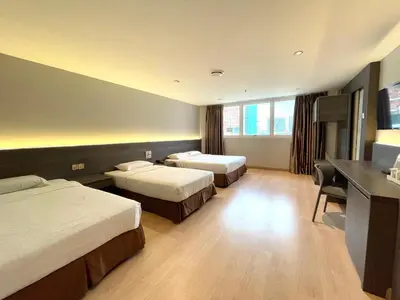 a hotel room with two beds and a desk at Hotel Imperial in Kuala Lumpur