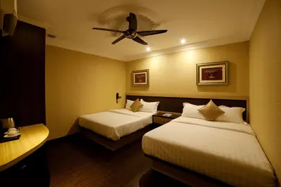a hotel room with two beds and a ceiling fan at Hotel Valenza in Kuala Lumpur