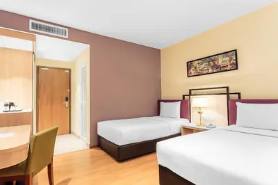 a hotel room with two beds and a desk at MPalace Hotel KL in Kuala Lumpur