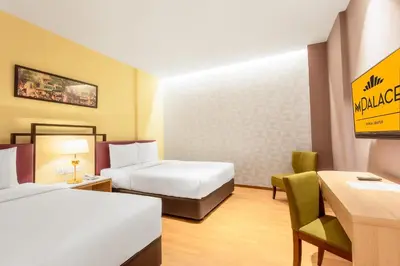 a hotel room with two beds and a desk and chair at MPalace Hotel KL in Kuala Lumpur