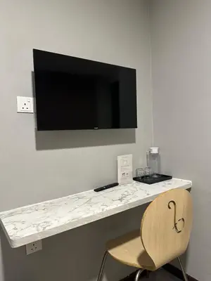 a desk with a television on a wall with a chair at D'Garden Hotel Kuala Lumpur in Kuala Lumpur