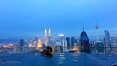 a couple in infinity pool with a city skyline at Maxhome@Regalia suite residence. KL in Kuala Lumpur
