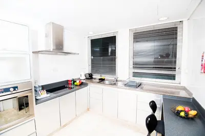 a kitchen with white cabinets and a black counter top at Perdana Kuala Lumpur City Centre in Kuala Lumpur