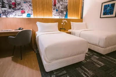 a hotel room with two beds and a desk and a chair at Indie Hotel Kuala Lumpur in Kuala Lumpur