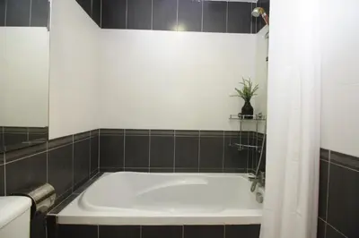 a bath tub in a bathroom with black tiles at UBN by Plush in Kuala Lumpur
