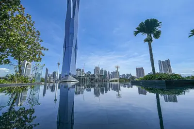 a view of a city with a skyscraper and a palm tree at Opus Residences by Opus Hospitality in Kuala Lumpur