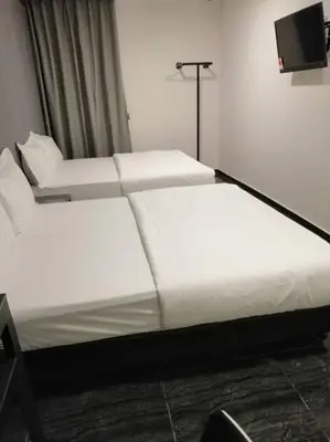 two white beds in a room with a tv at M Design Hotel @ Taman Pertama in Kuala Lumpur