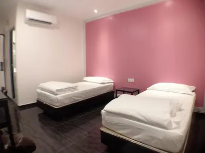 two beds in a room with a pink wall at M Design Hotel @ Taman Pertama in Kuala Lumpur