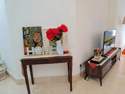 a room with a table with flowers and a tv at Bukit Bintang Apartment by Sarah's Lodge @ Fahrenheit88 in Kuala Lumpur