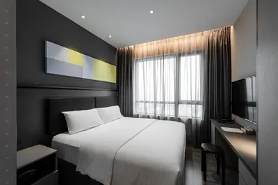 a bedroom with a bed and a desk and a window at Komune Living in Kuala Lumpur