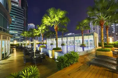 a resort with palm trees and a pool at night at Yemala Suites at Vortex KLCC in Kuala Lumpur