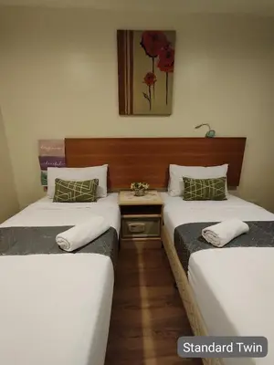 two twin beds in a hotel room with a table at SCC Hotel City Centre in Kuala Lumpur
