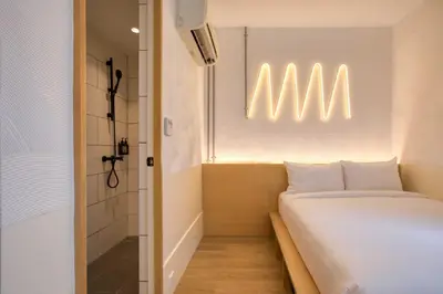 a small room with a bed and a shower at MoMo's Kuala Lumpur in Kuala Lumpur