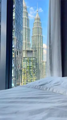 a bed with a view of a city skyline at Like Home Star KLCC in Kuala Lumpur