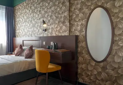 a bedroom with a bed and a mirror and a yellow chair at East Riverine Boutique Hotel in Kuala Lumpur