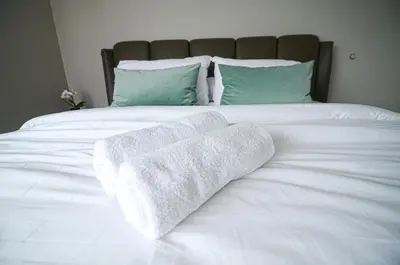 a white bed with two folded towels on it at Rafflesia Condominium by Dahlia Homes in Kuala Lumpur