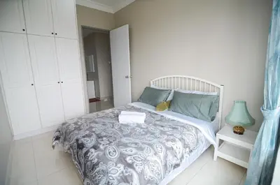 a bedroom with a bed with a gray and white comforter at Rafflesia Condominium by Dahlia Homes in Kuala Lumpur