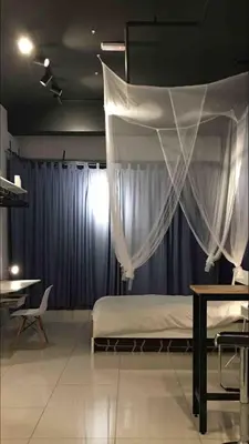 a bedroom with a bed with curtains and a table at Cozy Studio 10min to KLCC next to Hospital Gleneagle Jalan Ampang in Kuala Lumpur