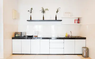 a kitchen with white cabinets and a black counter top at Boulevard Service Apartment KL by Airhost in Kuala Lumpur