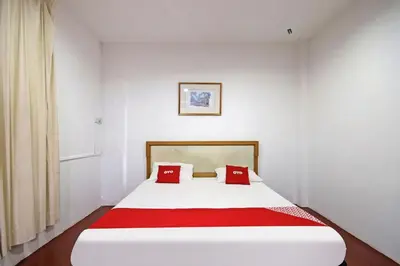 a white bed with red pillows in a room at Hotel O Shalimar in Kuala Lumpur