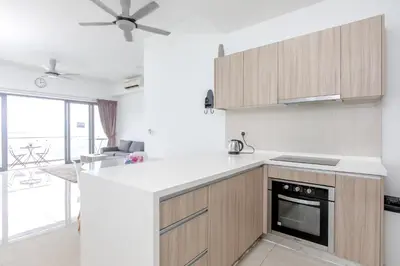 a kitchen with a white counter top and wooden cabinets at Rex Ollie @ The Elements Ampang in Kuala Lumpur