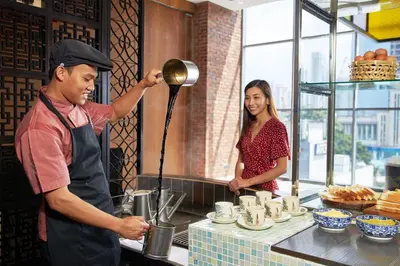 a man and a woman in a kitchen preparing food at Four Points by Sheraton Kuala Lumpur, Chinatown in Kuala Lumpur