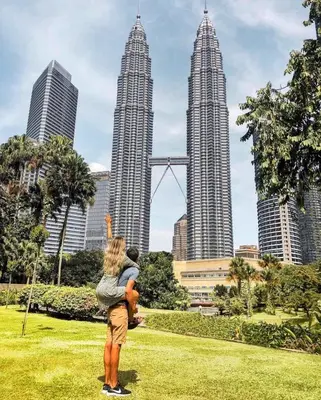 a woman holding a child in front of three tall buildings at WGS Suites at KLCC in Kuala Lumpur