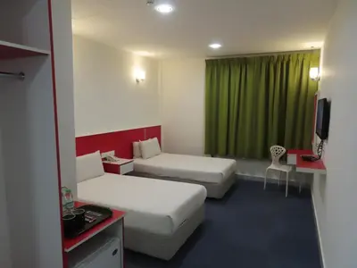 a hotel room with two beds and a green curtain at Akar Hotel Kampung Baru in Kuala Lumpur