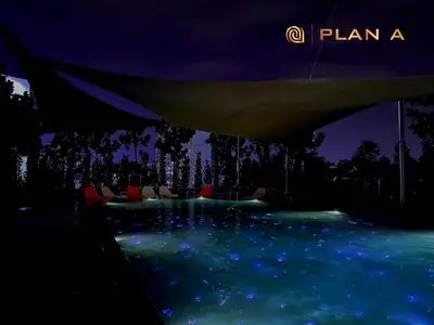 a swimming pool with chairs in the water at night at Opus KL Residences 1BR near TRX - Living Signature in Kuala Lumpur