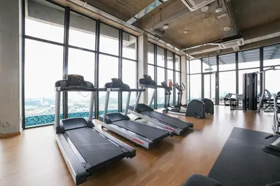 a gym with treadmills and ellipticals in a room with windows at Eko Cheras By Sleepy Bear in Kuala Lumpur