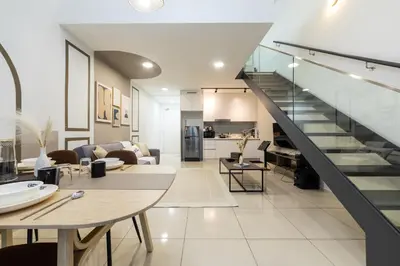 a living room and kitchen with a staircase in a house at Eko Cheras By Sleepy Bear in Kuala Lumpur