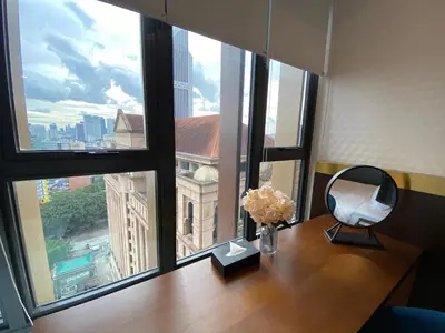a desk with a mirror and flowers on it in front of a window at Ceylonz Seasonal Suites in Kuala Lumpur