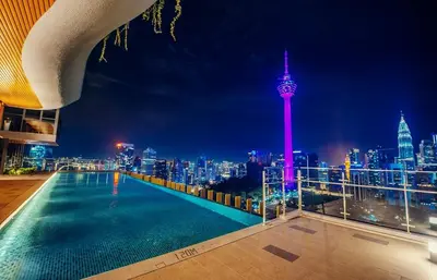 a rooftop pool with a view of the city at night at Ceylonz Seasonal Suites in Kuala Lumpur