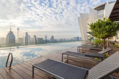 a rooftop pool with chairs and a view of the city at Regalia Suites Infinity Pool Kuala Lumpur in Kuala Lumpur