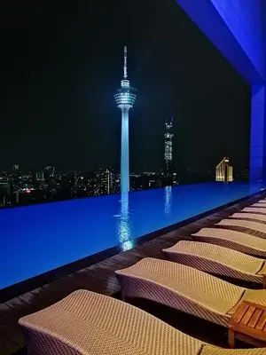 a rooftop bar with chairs and a view of the space needle at night at Yemala Suites at Platinum KLCC in Kuala Lumpur