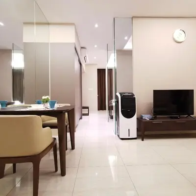 a living room with a tv and a table and a refrigerator at Dorsett Residences Kuala Lumpur in Kuala Lumpur