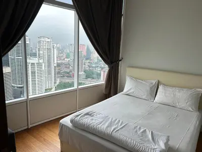 a bed in a room with a large window at KLCC City SkySuites in Kuala Lumpur